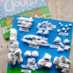 Finished cotton ball cloud craft laying on top of book called Clouds.