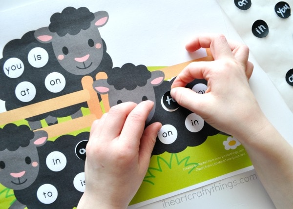 Child placing the matching sight word sticker on the printable.