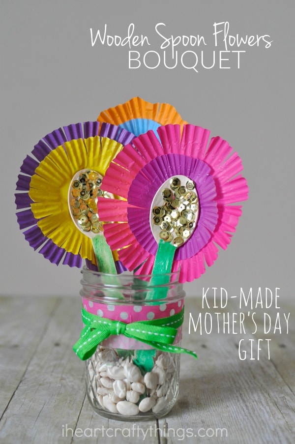 Vertical close up image of flower bouquet in a mason jar with the words "wooden spoon flower bouquet" in the top right corner and "kid-made mother's day gift" in the bottom right corner.