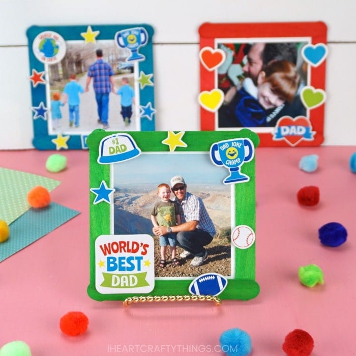 Square image of three Father's Day photo frame crafts. Front craft is in focus and back two are out of focus in front of a white shiplap background