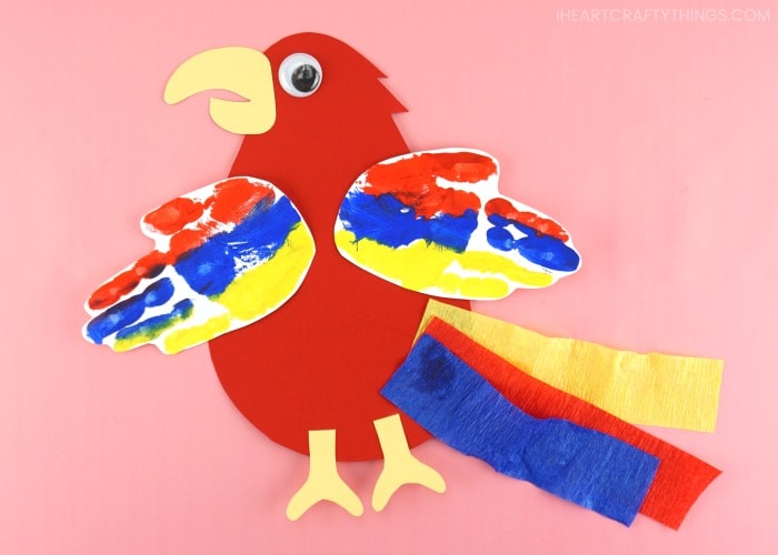 Horizontal image of finished parrot craft laying flat on pink background.