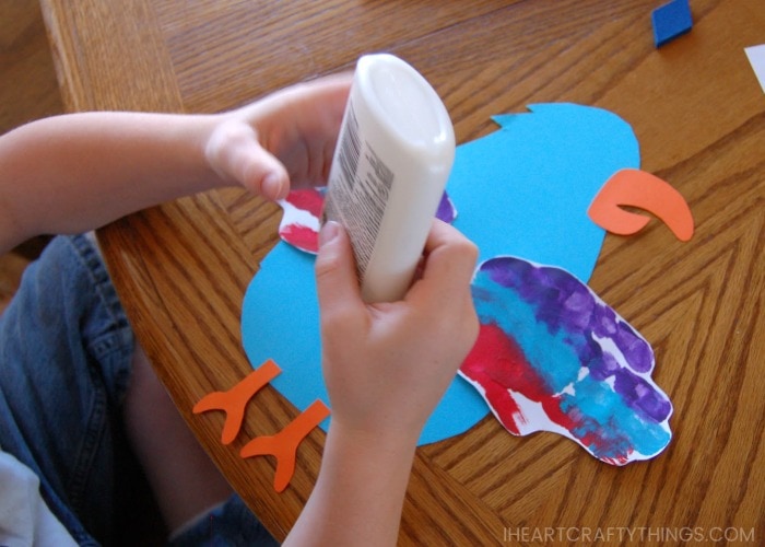 Child gluing pieces onto his parrot craft.