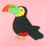 Completed kids toucan craft laying flat on a pink background.