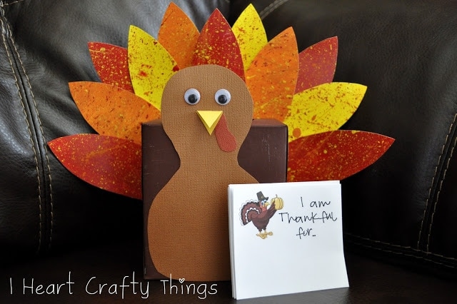 Close up image of finished thankful turkey box laying on a brown couch with writing prompt note cards propped up in front of the box.