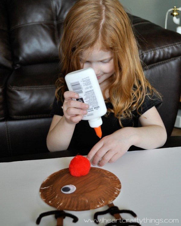 Image of child gluing the googly eyes onto her paper plate reindeer craft.