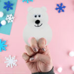 Close up image of adult with their fingers inside the polar bear finger puppet showing how to use it.