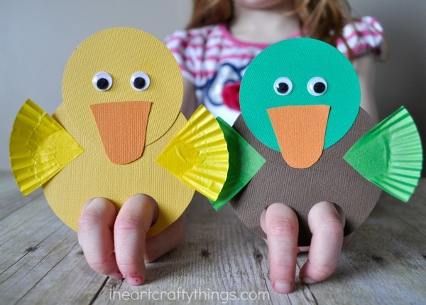 Child playing with a yellow duck and mallard duck finger puppets.