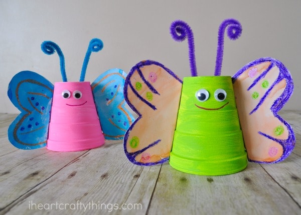 Green and purple butterfly craft in focus with a pink and blue butterfly craft out of focus in the background.