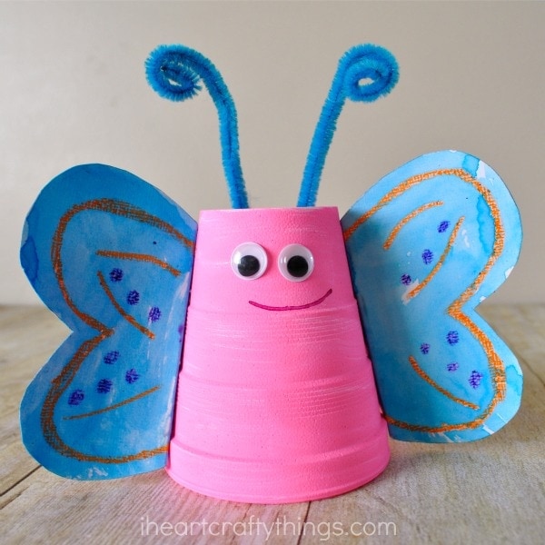 Close up image of pink foam cup butterfly craft with blue wings and blue antennae.