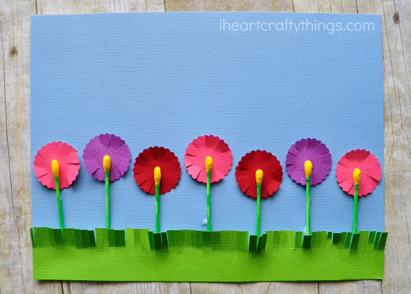 Completed q-tip flowers craft laying flat on a faux wood background.