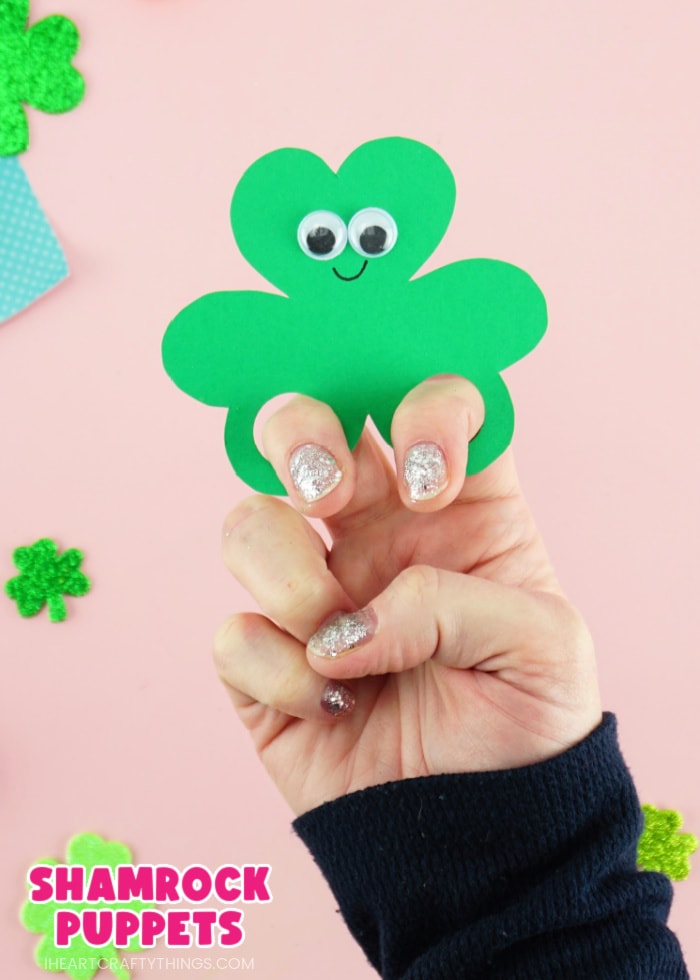 Vertical close up image of someone with their fingers in the shamrock finger puppet with the text "shamrock puppets" in the lower left corner.