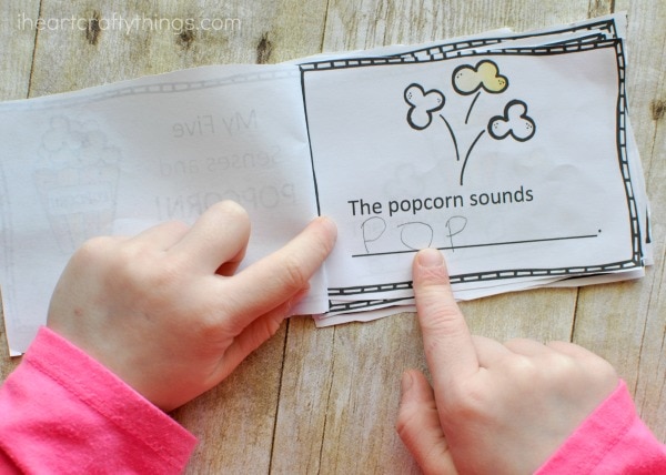 Preschool child using their finger to point to words and read the fives senses mini book.