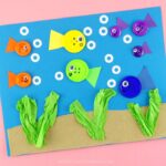 close up image of finished button fish craft on a pink background