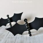 This clothespin button bat craft makes a great Halloween kids craft. It's so fun and versatile for Halloween. You can stand them up on a shelf as a cute Halloween decoration, add a magnet to the back of them and use them to hold up other artwork on your fridge or string a line of them together and make a fun bat banner for a Halloween decoration.