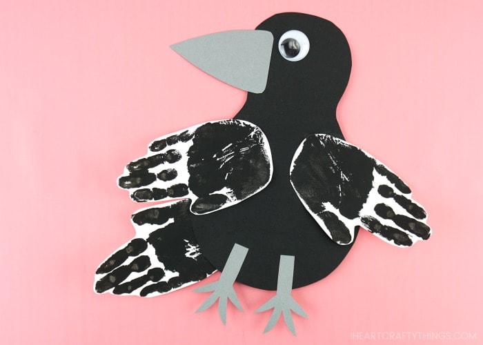 handprint raven craft laying flat on a pink background