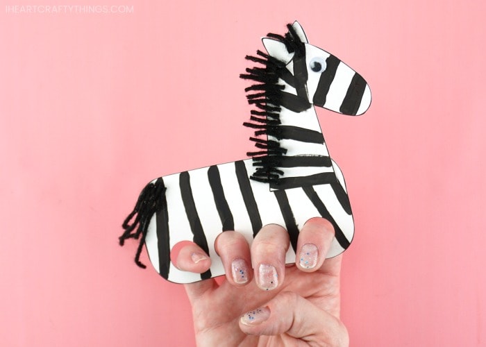 Close up image of adult demonstrating how to place four fingers in the zebra puppet.