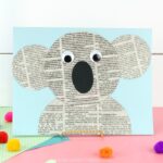 newspaper koala craft propped up on a pink table with a white shiplap background