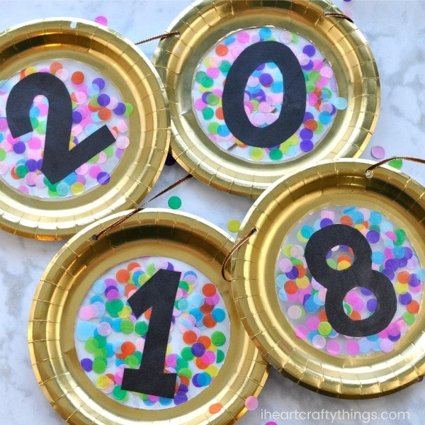 Make your New Year's Party extra festive by making this paper plate New Year's Eve Banner. It's the perfect festive compliment for a New Year's Eve party since it is made with black, gold and colorful confetti. You won't believe how easy it is to put together. Fun New Year's Eve crafts for kids.