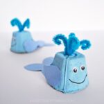 square image of two egg carton whale crafts with one in focus in the front and one out of focus in the back