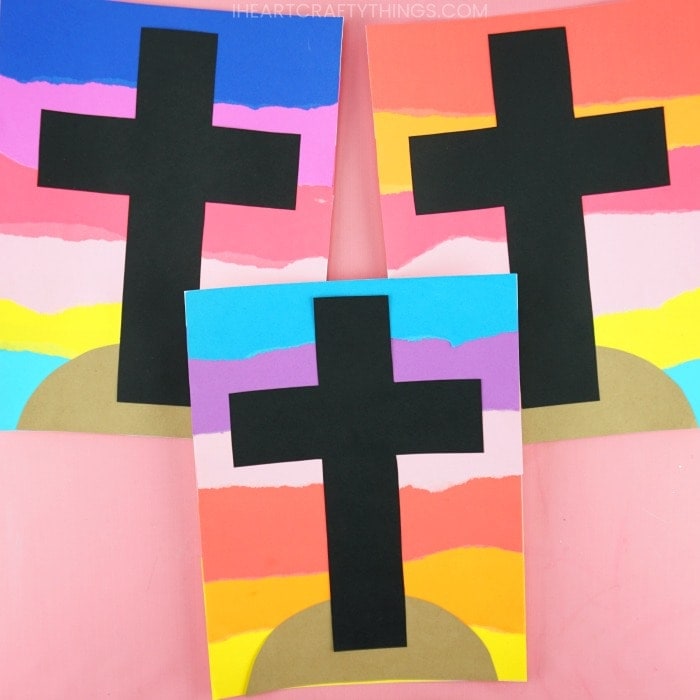three easter cross crafts laying flat on a pink background