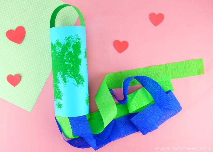 earth day windsock craft laying flat on a pink background with scattered red hearts