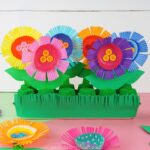 egg carton flower garden craft for kids laying on a pink table with a white shiplap background