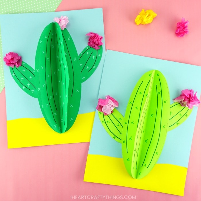 dark green and light green paper cactus craft laying flat together on a pink background