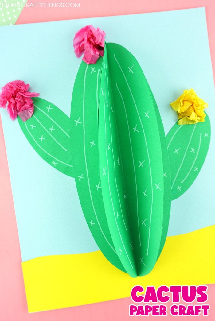 vertical image of paper cactus craft laying flat on a pink background