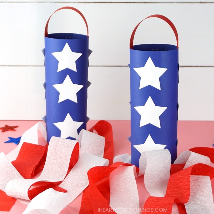 two red white and blue patriotic windsocks sitting on a pink table with a white shiplap background