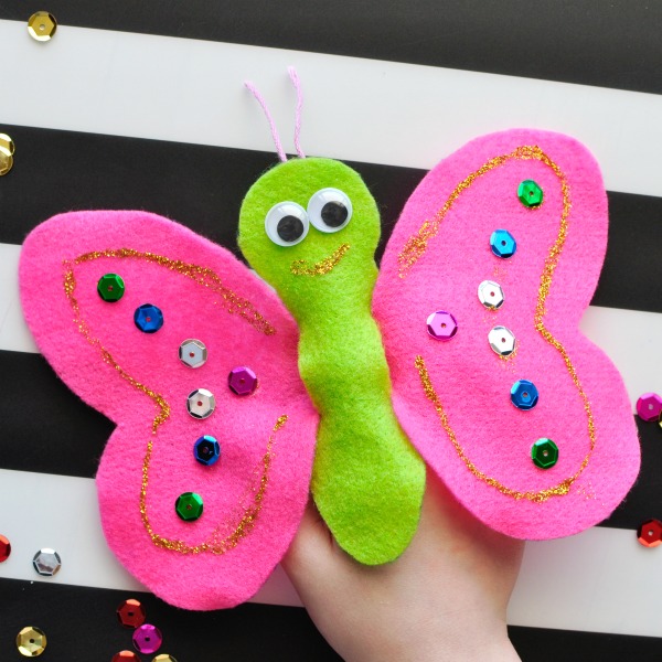 Child playing with a pink and green felt butterfly puppet.