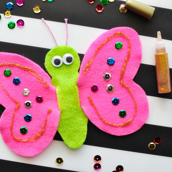 Square close up image of decorating butterfly finger puppet with sequins and glitter glue.