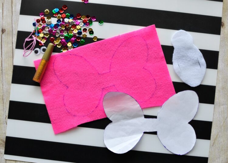 supplies for making butterfly finger puppet laying out on a black and white striped placemat.