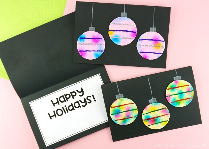 Close up image of three homemade Christmas cards with one laying open showing "Happy Holidays" on the inside of the card.