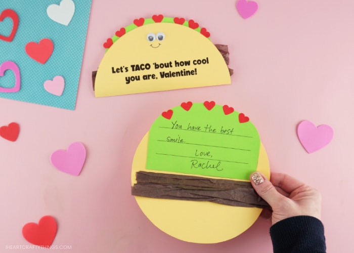 Image showing an adult holding open the taco Valentine's Day card showing the message written on the inside that reads "You have the best smile! Love, Rachel".