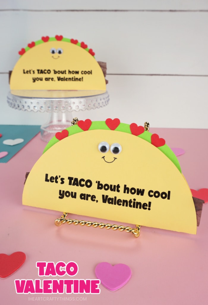 Vertical image of two taco Valentine's Day cards propped up with the front taco up close and in focus and the back taco out of focus. Text "Taco Valentine" in the bottom left corner of image.