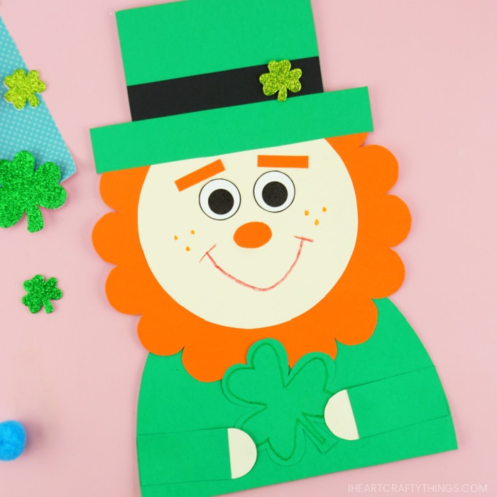 Close up image of leprechaun paper craft laying on a pink background.