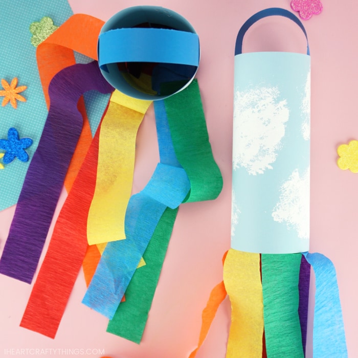 Two rainbow windsocks with the one on the left laying flat and the one on the left standing up with the rainbow strips flowing out of the bottom of it.