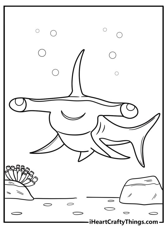 Hammerhead shark swimming above sandy ocean floor coloring page